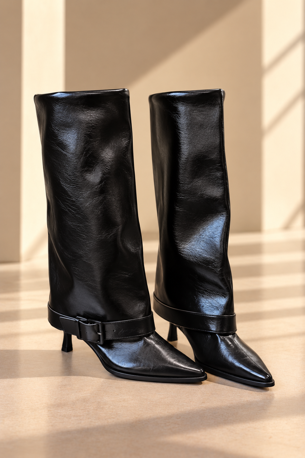 Botas altas de cuero BY MANAY en negro — caña alta, punta estilizada, tacón fino, acabado brillante y correa con hebilla en el tobillo.