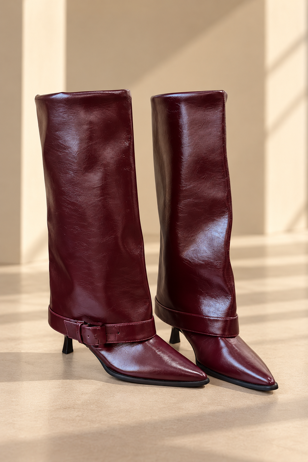 Botas altas de cuero BY MANAY en burdeos — caña alta, punta estilizada, tacón fino, acabado brillante y correa con hebilla en el tobillo.