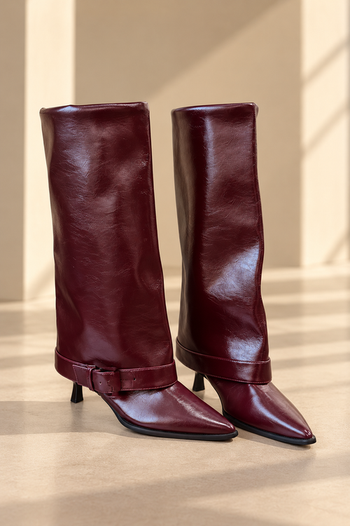 Botas altas de cuero BY MANAY en burdeos — caña alta, punta estilizada, tacón fino, acabado brillante y correa con hebilla en el tobillo.